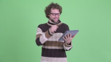 Heyecanlı genç sakallı adam kullanarak ve dijital tablet gösteren