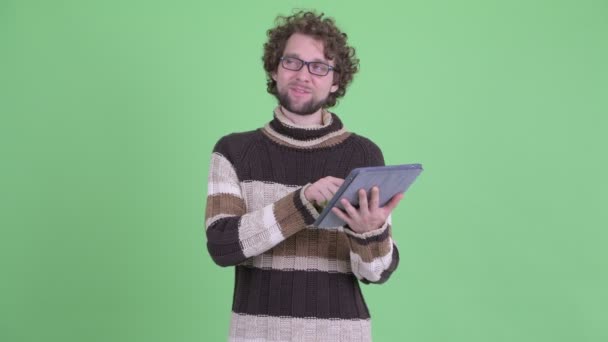 Feliz joven barbudo hombre pensando mientras se utiliza la tableta digital — Vídeos de Stock