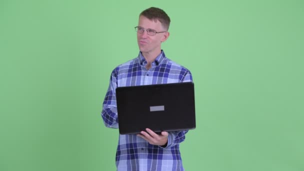 Portret van Happy hipster man denken tijdens het gebruik van laptop — Stockvideo