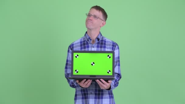 Retrato de hombre hipster feliz pensando mientras muestra el ordenador portátil — Vídeos de Stock