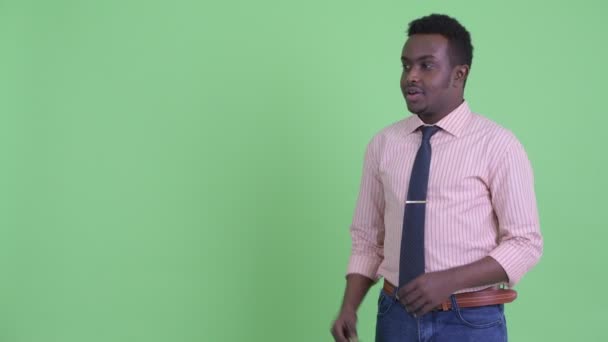 Ευτυχισμένος νεαρός Αφρικανός επιχειρηματίας που δαγκώνει τα δάχτυλα και μιλάει — Αρχείο Βίντεο