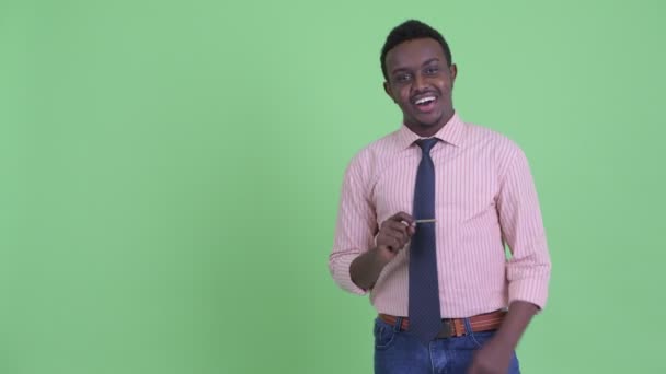 Счастливый молодой африканский бизнесмен говорит и трогает что-то — стоковое видео