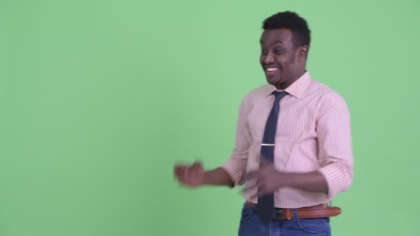 Glücklicher junger afrikanischer Geschäftsmann schaut aufgeregt, während er etwas zeigt — Stockvideo