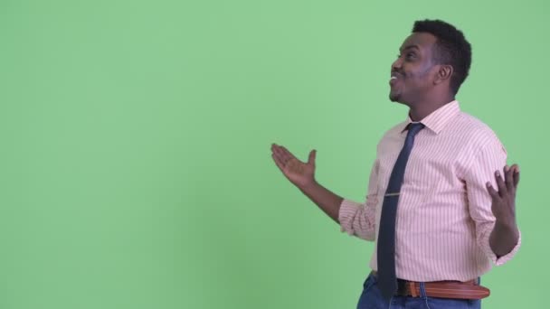 Счастливый молодой африканский бизнесмен щелкает пальцами и выглядит удивленным — стоковое видео