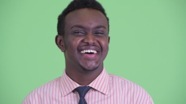 Лицо счастливого молодого африканского бизнесмена, улыбающегося и смеющегося — стоковое видео