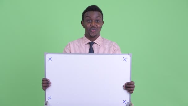 Gelukkige jonge Afrikaanse zakenman die wit bord vasthoudt en op zoek is verrast — Stockvideo