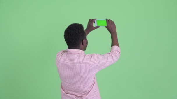 Vista posteriore del giovane imprenditore africano che scatta foto con il telefono — Video Stock