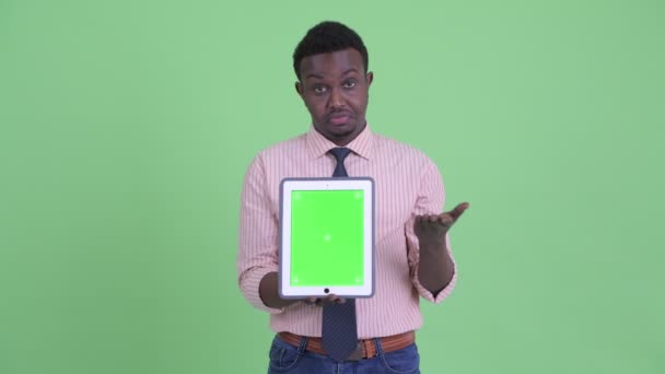 Стрессовый молодой африканский бизнесмен показывает цифровой планшет — стоковое видео
