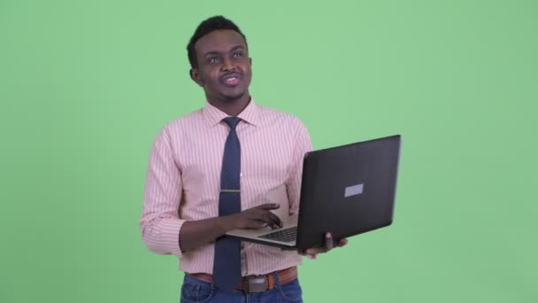 Ευτυχισμένος νέος Αφρικανός επιχειρηματίας σκέψης κατά τη χρήση laptop — Αρχείο Βίντεο
