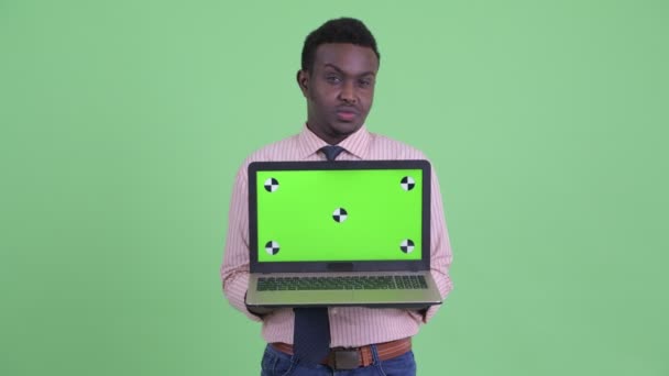 Stresli genç Afrikalı işadamı dizüstü bilgisayar gösteren — Stok video