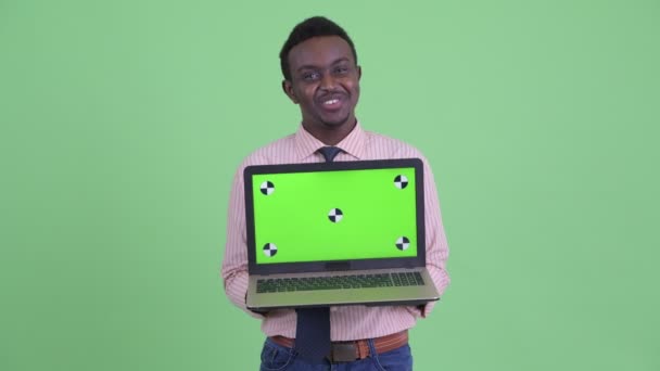 Счастливый молодой африканский бизнесмен разговаривает, показывая ноутбук — стоковое видео