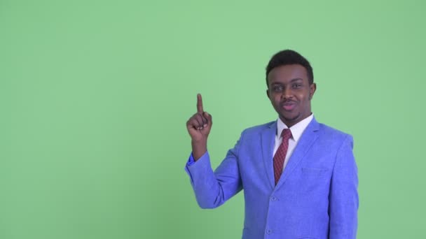Gelukkige jonge Afrikaanse zakenman die praat terwijl hij naar boven wijst — Stockvideo