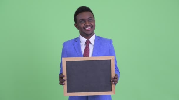 Счастливый молодой африканский бизнесмен думает, держа доску — стоковое видео