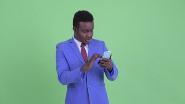Mutlu genç Afrikalı işadamı telefon kullanarak ve iyi haber alma