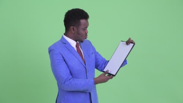Стрессовый молодой африканский бизнесмен показывает планшет и показывает большие пальцы вниз — стоковое видео