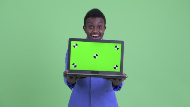 Šťastný mladý africký obchodník zobrazující notebook a překvapený — Stock video