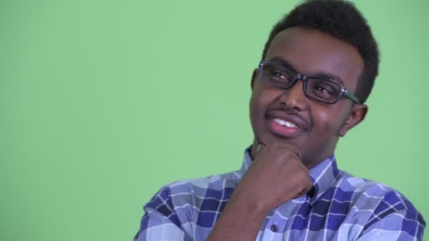 Tvář šťastného mladého afrického hipstera, který uvažuje s brýlemi — Stock video