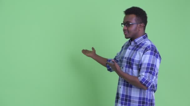 Szczęśliwy młody afrykański Hipster człowiek pokazując coś na plecach — Wideo stockowe