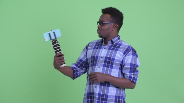 Mutlu genç Afrikalı hipster adam vlogging ve telefon gösteren — Stok video