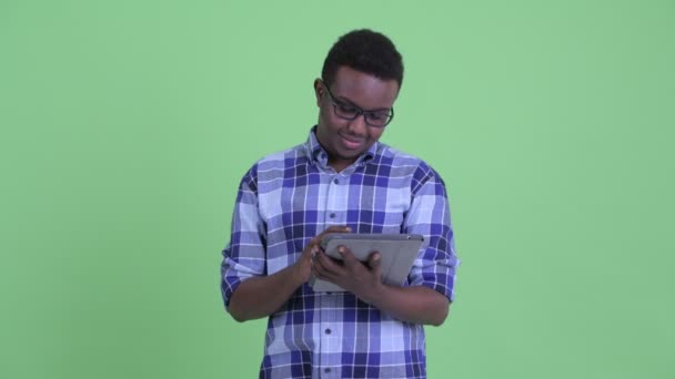 Feliz jovem homem hipster Africano pensando ao usar tablet digital — Vídeo de Stock