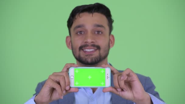 Gesicht eines glücklichen jungen bärtigen persischen Geschäftsmannes, der sein Handy zeigt — Stockvideo