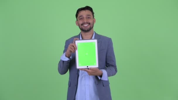 Щасливий молодий бородатий перський бізнесмен говорити, показуючи цифровий планшет — стокове відео