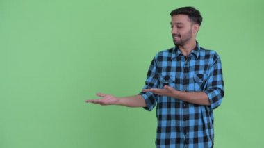 Mutlu genç sakallı Farsça hipster adam bir şey gösteren