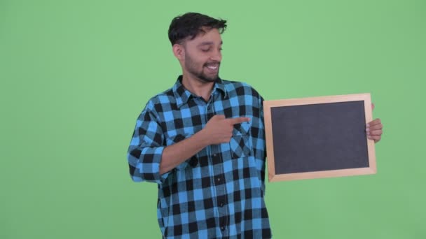 Счастливый молодой бородатый персидский хипстер держит доску и показывает большие пальцы — стоковое видео