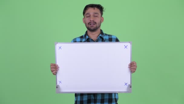 Stressed young bearded Persian hipster man holding white board — Stock Video