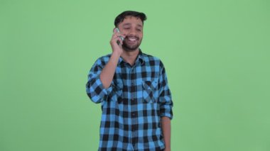 Mutlu genç sakallı Farsça hipster adam telefonda konuşuyor
