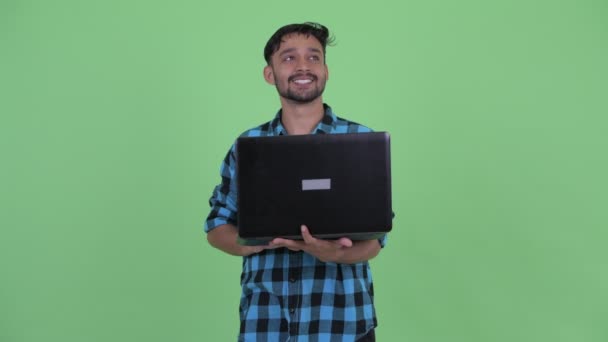 Mutlu genç sakallı Farsça hipster adam dizüstü bilgisayar kullanırken düşünme — Stok video