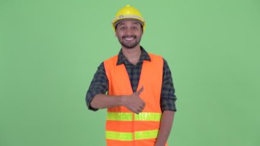 Mutlu genç sakallı Pers adam inşaat işçisi başparmak veren