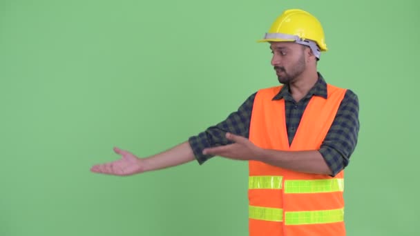 Щасливий молодий бородатий Перська людина працівник будівництва показуючи щось — стокове відео