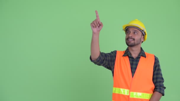 Счастливый молодой бородатый перс строитель указывает вверх — стоковое видео