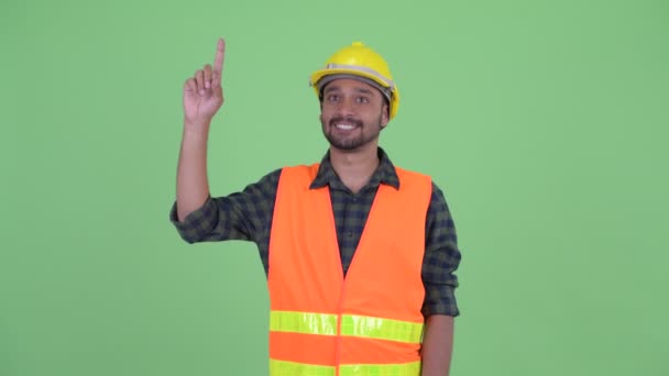 Feliz joven barbudo persa trabajador de la construcción apuntando hacia arriba — Vídeos de Stock