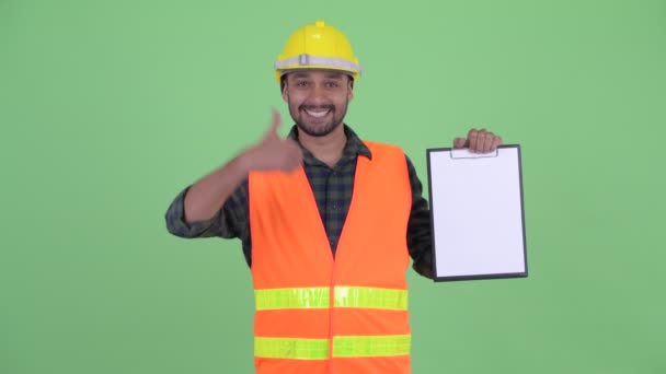 Boldog fiatal szakállas perzsa ember építőipari munkás bemutató vágólapra, és amely remek — Stock videók