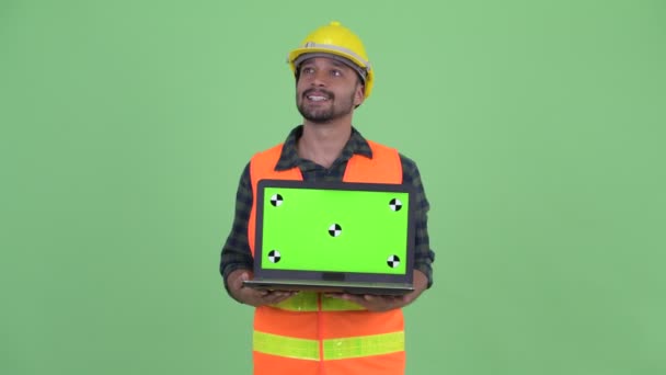 Feliz jovem barbudo persa homem construção trabalhador pensando ao mostrar laptop — Vídeo de Stock