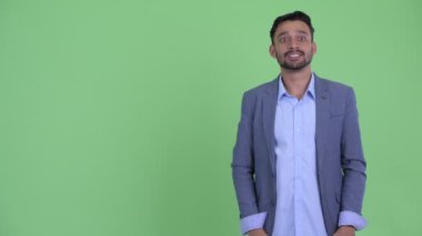 Mutlu genç sakallı İranlı işadamı parmaklarını şıklatma ve bir şey sunan