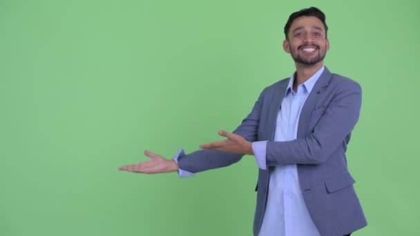 Happy young bearded Persian businessman presenting something — Stock Video