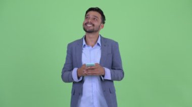 Mutlu genç sakallı İranlı işadamı telefon kullanırken düşünme