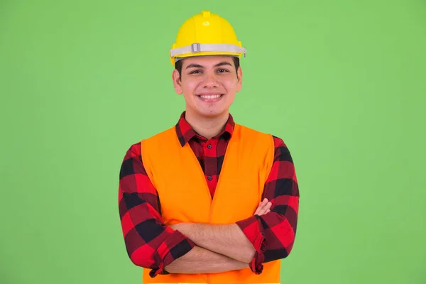 Lycklig ung multietnisk man byggnadsarbetare leende med armarna korsade — Stockfoto