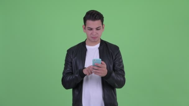 Šťastný mladý pohledný multietnický muž, který používá telefon a dostává dobré zprávy — Stock video