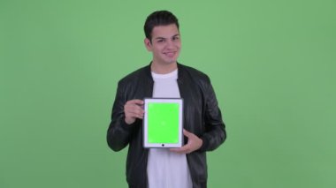 Mutlu genç yakışıklı çok etnik adam düşünme dijital tablet gösterirken