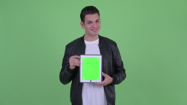 Jovem feliz bonito multi etnia homem pensando ao mostrar tablet digital — Vídeo de Stock