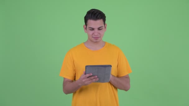 Boldog fiatal többnemzetiségű ember gondolkodás használata közben a digitális tabletta — Stock videók