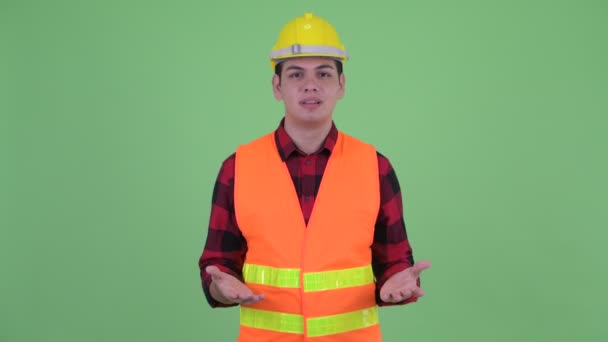 Щасливий молодий багатонаціональний працівник будівництва, який щось пояснює — стокове відео