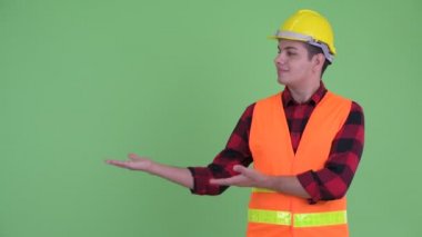 Mutlu genç çok etnik adam inşaat işçisi bir şey gösteren