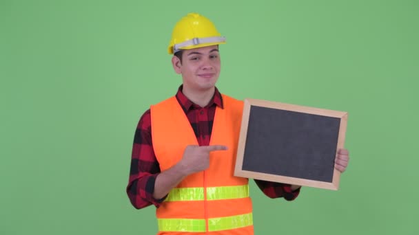 Heureux jeune homme multi ethnique travailleur de la construction tenant tableau noir et donnant pouces vers le haut — Video