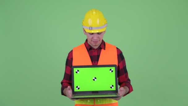 Happy Young multi etnisk man konstruktion Worker tänkande när du visar laptop — Stockvideo