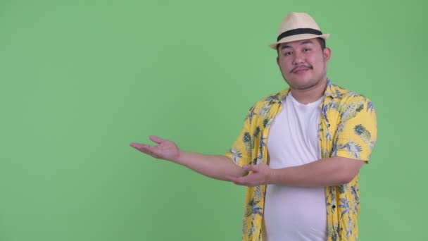 幸せな若い太りすぎのアジアの観光客の男は何かを示し、親指を与える — ストック動画